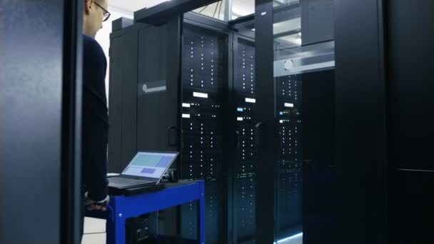 Server ingenieur wandelingen in datacenter met Crash Cart. Hij loopt langs rijen Server Racks te werken. — Stockvideo