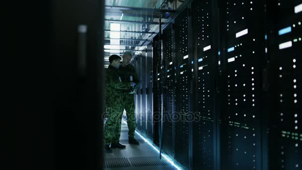 Στο κέντρο δεδομένων δύο στρατιωτική τους άνδρες λειτουργούν με ανοιχτό διακομιστή Rack ερμάριο. Κρατά το Laptop στρατιωτική έκδοση. — Αρχείο Βίντεο