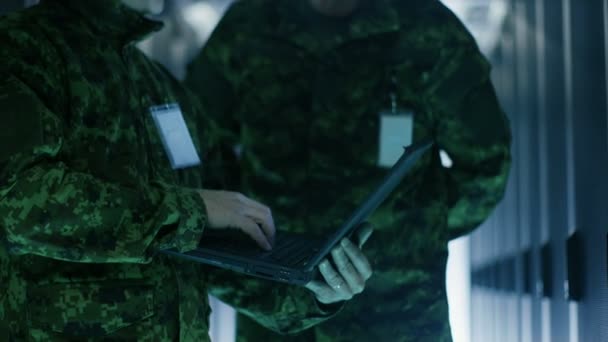 Στο κέντρο δεδομένων δύο στρατιωτική τους άνδρες λειτουργούν με ανοιχτό διακομιστή Rack ερμάριο. Κρατά το Laptop στρατιωτική έκδοση. — Αρχείο Βίντεο