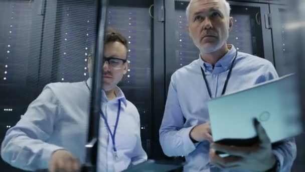 Beelden geschoten van Rack Server kabinet. Twee het technici gebruik Laptop en Tablet PC werken over Hardware en Software. — Stockvideo