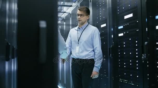 Twee Corporate werknemers schudden handen in begroeting. Ze werken in moderne datacenter met rijen van Server Racks. — Stockvideo