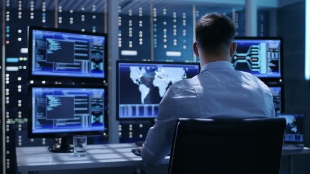 Back View of Technical Controller / Operatør, der arbejder på sin arbejdsstation med flere skærme. Muligt kraftværk / lufthavn afsender / dæmningsarbejder / regeringsovervågning / rumprogram – Stock-video
