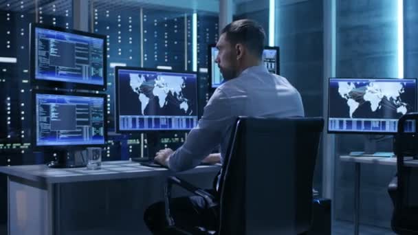 Teknisk Controller arbetar på sin arbetsplats med flera bildskärmar. Han är ensam i System Control Center. — Stockvideo