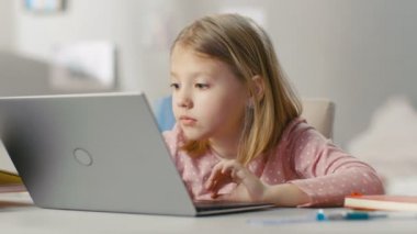 Sevimli genç kız kullanır dizüstü Her ışık odasındaki masada otururken bilgisayar.