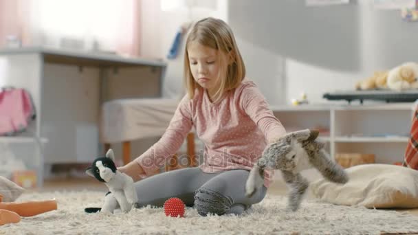 Jeune fille mignonne joue avec des jouets en peluche tout en étant assis sur un tapis dans sa chambre lumineuse et confortable . — Video