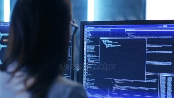 Über die Schulter Aufnahmen von weiblichen IT-Ingenieurinnen, die im Überwachungsraum arbeiten. sie arbeitet mit mehreren Displays. — Stockvideo