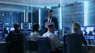 Profesyonel mühendis sistem kontrolü ortasında çalışma monitörler ve sunucular ile dolu. Muhtemelen devlet kurumu yürütmektedir soruşturma. 