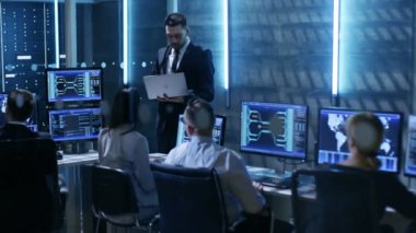 Profesyonel mühendis sistem kontrolü ortasında çalışma monitörler ve sunucular ile dolu. Gözetmen Laptop tutar ve bir brifing aldı. Muhtemelen devlet kurumu yürütmektedir soruşturma. 