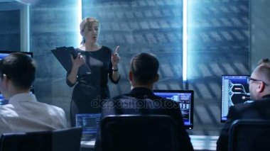 Hükümet sistemi kontrol merkezi. Kadın yönetici toplantı ekibi teknik profesyoneller için tutar. Onlar çalışma alanı birden fazla gösterilen çeşitli bilgileri görüntüler ile donatılmıştır.