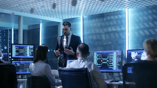 Supervisore tiene briefing per i suoi dipendenti in System Control Center pieno di monitor e server. Possibilmente l'agenzia governativa conduce le indagini . — Video Stock