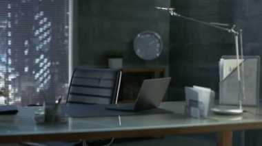 Deri koltuk, ahşap ve cam masa Laptop onu çalışma alanı ile Modern bir ofis görüntüleri ile karanlık Overtones yapılır, Big City pencereden görülür.