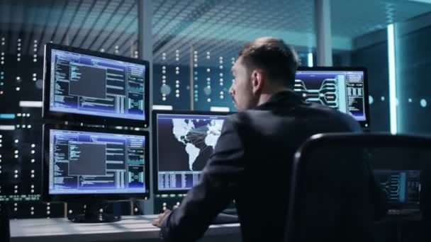 Back View of Technical Controller / Operatør, der arbejder på sin arbejdsstation med flere skærme. Muligt kraftværk / lufthavn afsender / dæmningsarbejder / regeringsovervågning / rumprogram – Stock-video