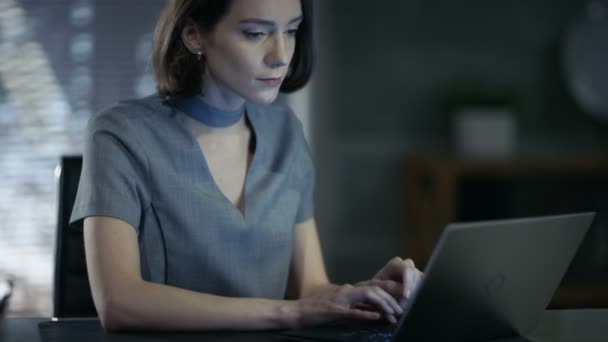 Stylowy kobieta Top Manager działa na laptopie w jej gabinecie. Jej obszar roboczy jest nowoczesne, wykonane w podteksty ciemne, Duże miasta widać z okna. — Wideo stockowe