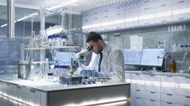 Araştırma bilim adamı görünüyor içine mikroskop ve gözlemler aşağı yazıyor. Modern laboratuvar deneylerinde yürütmektedir o.