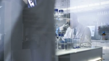 Meşgul bir Modern laboratuvar olarak iki bilim adamları deneyler. Baş araştırma bilim asistanı için mikroskop içinde gördüğü sonuçları belirler.