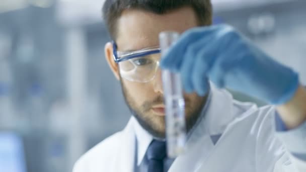 En un laboratorio moderno Científico realiza experimentos mediante la síntesis de compuestos con el uso de gotero y planta en un tubo de ensayo . — Vídeo de stock