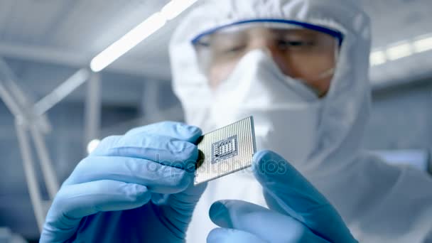 超近代的な電子製造工場設計エンジニア滅菌カバーオールを保持しているマイクロ チップに手袋、調べますとそれ. — ストック動画
