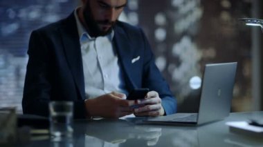 İşadamı kullanır büyük şehir penceresi görünümü ile O'nun özel ofisinde otururken Smartphone.