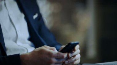 İşadamı kullanır büyük şehir penceresi görünümü ile O'nun özel ofisinde otururken Smartphone.