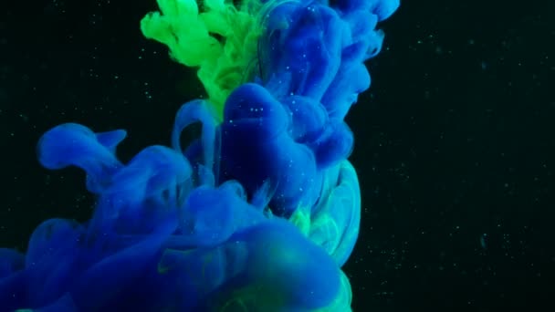 Mezclas de pintura de neón verde y azul en el espacio oscuro . — Vídeos de Stock