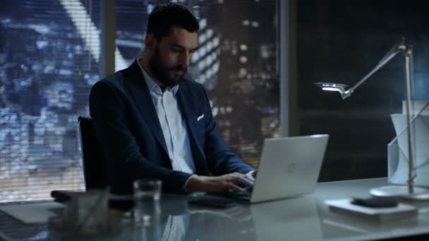 Empresario trabaja en una computadora portátil en su oficina privada con vista a la ventana de Big City . — Vídeo de stock