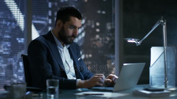 Późno w nocy w prywatne biuro biznesmen działa na laptopie. Jego następcą na całym świecie zdobywając duży kontrakt. Jest bardzo zadowolony. — Wideo stockowe
