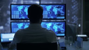 Geç gece güvenlik operatör dikkatle üzerinde gösterilen konumu hassas bilgileri onun monitörlerle gözlemler. 