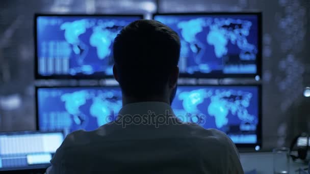 Late at Night Security Operator observa atentamente a sus monitores con información sensible de la ubicación que se muestra en ellos . — Vídeo de stock