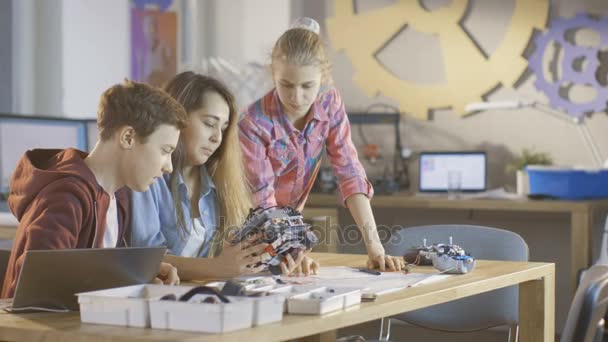 Duas meninas e um menino trabalham no projeto de robótica da classe de ciência. Estão a construir um robô móvel do construtor. . — Vídeo de Stock