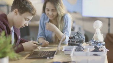 Kız ve oğlan Program Laptop kendi bilim / robot / Mühendislik elektronik cihazla okulda sınıf.