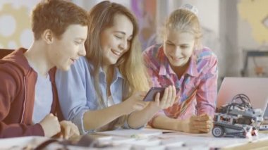 Çocuk ve iki kız okul bilim sınıf projede çalışan smartphone cep telefonu ile popüler Videolar İzle.