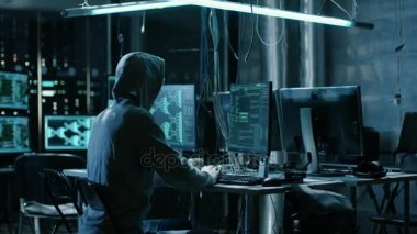Kukuletalı Hacker kurumsal veri sunucuları ve Infects onları virüs ile tatili. Onun saklanma yerine karanlık atmosfer, birden çok ekran, kabloları her yerde vardır.
