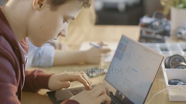 Смарт молодий хлопець працює на ноутбуці для свого нового проекту в своєму комп'ютерних наук класі . — стокове відео