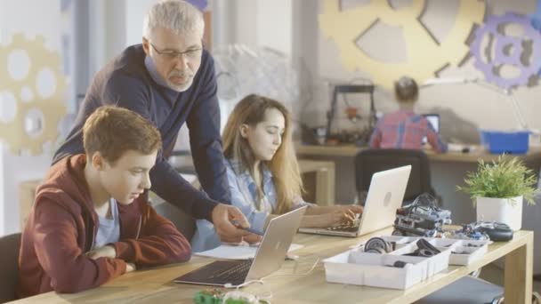 Die Lehrerin arbeitet mit kleinen Jungen und Mädchen in einem Informatikunterricht. Kinder nutzen Laptops. — Stockvideo