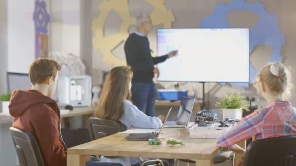 In einer Informatikklasse erklärt Lehrer das Programmieren und zeigt es auf interaktivem Whiteboard. — Stockvideo
