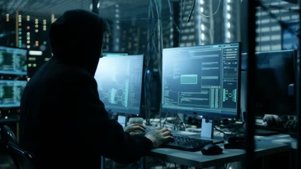 두건된 해커와 그의 그룹 회사 데이터 서버에 휴식. 어두운 분위기, 다중 디스플레이 케이블 어디에 나 있다. — 비디오