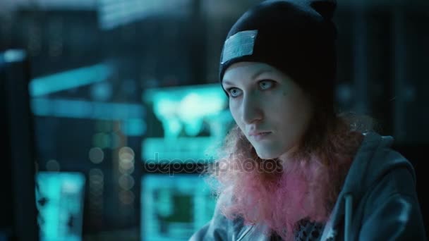 Conformistische Teenage Hacker meisje met roze haar aanvallen bedrijfsservers met Malware. Kamer is donker, Neon en heeft vele Displays. — Stockvideo