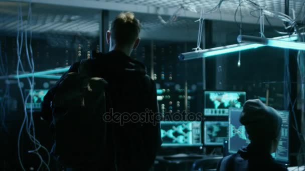 Hooded Hacker prend sa place à son bureau dans la tanière de Hacker. Lieu est néon, sombre et a de nombreux affichages ,