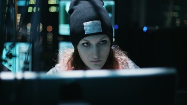 Nonkonformistisches Teenager-Hackermädchen mit rosa Haaren greift Unternehmensserver mit Malware an. Raum ist dunkel, neon und hat viele Displays. — Stockvideo