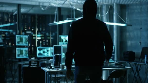 Hooded Hacker prend sa place à son bureau dans Hacker's Den. Lieu est néon, sombre et a de nombreux affichages ,