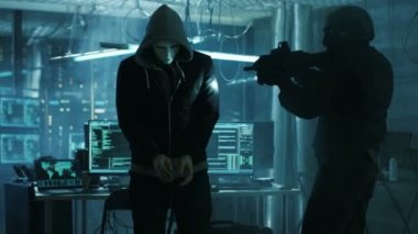 Maskeli Hacker kelepçe takan tamamen silahlı Özel Kuvvetler asker tarafından korunuyor. Hacker'ın saklanma Bodrum ile birden çok çalışma göstermek onlar.