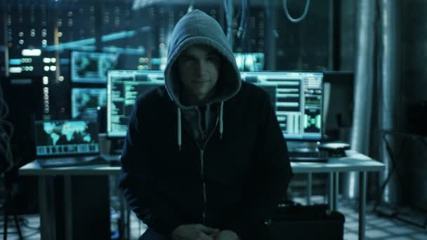 Ein international gesuchter Hacker spricht in die Kamera. im Hintergrund sein Operationssaal mit mehreren Displays und Kabeln. — Stockvideo