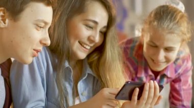 Çocuk ve iki kız okul bilim sınıf projede çalışan smartphone cep telefonu ile popüler Videolar İzle.