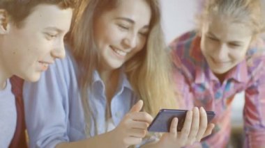 Çocuk ve iki kız okul bilim sınıf projede çalışan smartphone cep telefonu ile popüler Videolar İzle.