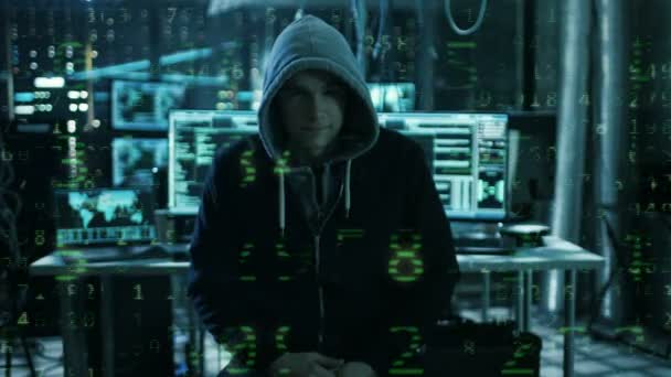 Der gefährliche, international gesuchte Hacker spricht in die Kamera, mit verregnetem Zahlencode-Effekt. im Hintergrund sein Operationssaal mit mehreren Displays und Kabeln. — Stockvideo