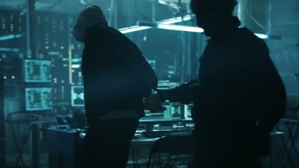 Agent de cybersécurité des forces spéciales arrestations, menottes et emporte pirate très dangereux. En arrière-plan Moniteurs complets et dispositifs de piratage de la tanière du pirate .