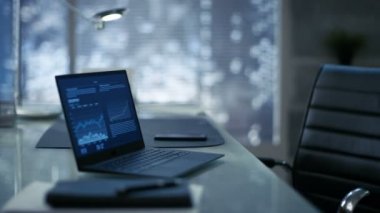 Deri koltuk, ahşap ve cam masa Laptop onu çalışma alanı ile Modern bir ofis görüntüleri ile karanlık Overtones yapılır, Big City pencereden görülür.