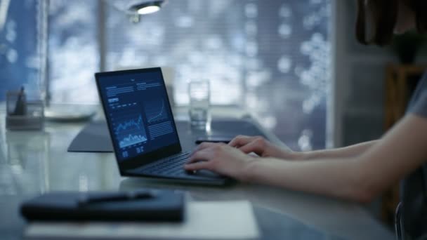 Close-up of Young Businesswoman Siting at Her Working Table and Typing on a Laptop. Her Office Looks Modern with Dark Overtones, Big City Behind the Window. — Stock Video
