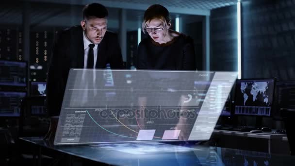 Manager und Managerinnen nutzen interaktives 3D-Panel mit Touchscreen in großem Überwachungsraum voller Computer mit animierten Bildschirmen. — Stockvideo