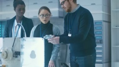 Üç çok parlak ve genç çok ırklı öğrenciler yeni bir Modern laboratuvar 3D yazdırılan mekanizması tartışıyor.